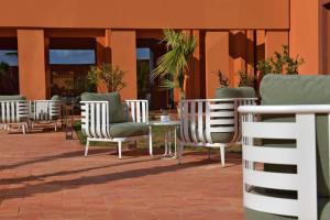 Doubletree By Hilton Ben Guerir Hotel & Residences في Benguerir: صف من الكراسي والطاولات على الفناء