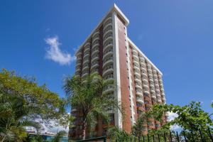 a tall building with a palm tree in front of it at Flat Barra First - Morada Stay in Rio de Janeiro