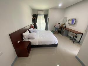 a bedroom with a bed and a desk and a person at SUPATTRA PLACE ( สุพัตราเพลส ) in Pai