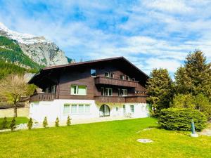 una casa grande en las montañas con césped verde en Bellevue & Classy Mountain View apartment, en Kandersteg