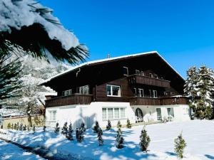 una gran casa de madera en la nieve con árboles en Bellevue & Classy Mountain View apartment, en Kandersteg