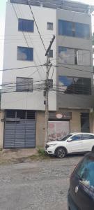 a white car parked in front of a building at apart hotel big john 102 in Divinópolis