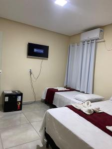 倫索伊斯的住宿－Pousada Vista da Serra - Suzart，客房设有两张床和一台墙上的电视。
