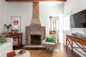 a living room with a brick fireplace and a tv at Green Cottage at Casa Zoe in Charleston