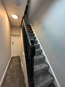 a staircase in a home with grey carpet at Ashley’s Place in Manchester