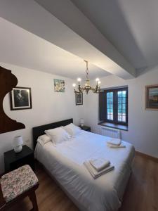 a bedroom with a bed with white sheets and a chandelier at Apartamento El rincón del Gato in Santillana del Mar