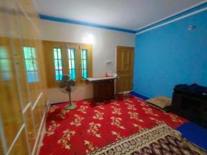 um quarto com um tapete vermelho e paredes azuis em Sharian Guest House em Lamniān