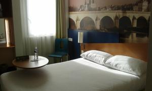 a bedroom with a bed and a table and a window at ibis Styles Orléans in La Chapelle-Saint-Mesmin