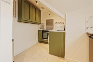 a kitchen with green cabinets and a white microwave at Lamara Flat 3, Liverpool in Liverpool