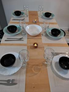 a wooden table with plates and wine glasses on it at Appartement Spacieux 80 m2 in Bobigny