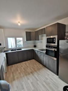 a kitchen with wooden cabinets and a stainless steel refrigerator at Appartement Spacieux 80 m2 in Bobigny