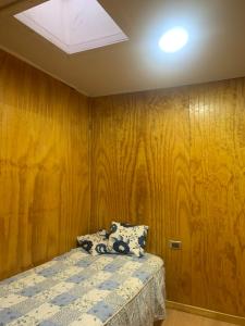 1 dormitorio con 1 cama con pared de madera en Hospedaje Canela, en Osorno