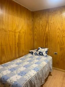 1 dormitorio con 1 cama con pared de madera en Hospedaje Canela, en Osorno