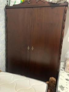a brown cabinet with two doors next to a bed at Casa de aluguel mobiliada in Sarandi