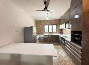 a kitchen with a white counter and a refrigerator at Queen's 2 BDR Appartments Accra in Chantan