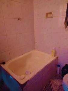 uma banheira na casa de banho com azulejos cor-de-rosa em Casa familiar orange corner em La Paz