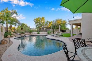 una piscina en un patio con sillas y sombrilla en Pool, Putting Green, Arcade, Cornhole, Great Location at Phoenix Desert Ridge Retreat! en Phoenix