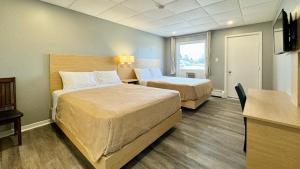a hotel room with two beds and a desk at SUMMERSIDE MOTEL &COTTAGES in Summerside