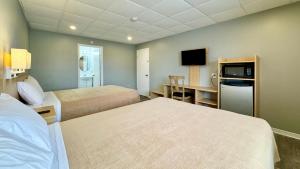 Habitación de hotel con 2 camas y escritorio con TV. en SUMMERSIDE MOTEL &COTTAGES en Summerside
