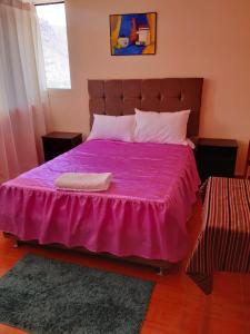 a bedroom with a purple bed with a purple blanket at Hostal Ayllu in Urubamba