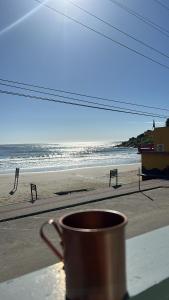 a coffee cup sitting on a table in front of a beach at Pousada Sol e Mar in Farol de Santa Marta