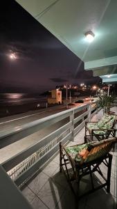 two benches sitting on a balcony at night at Pousada Sol e Mar in Farol de Santa Marta