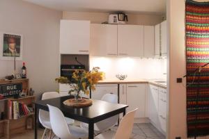 a kitchen with white cabinets and a table and chairs at Charming and practical studio in Paris 14th in Paris