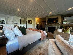Queenstown House Bed & Breakfast and Apartments في كوينزتاون: غرفة نوم بسرير كبير ومدفأة