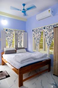 ein Schlafzimmer mit einem Bett mit blauen Wänden und einem Fenster in der Unterkunft Ichhepuron in Shānti Niketan