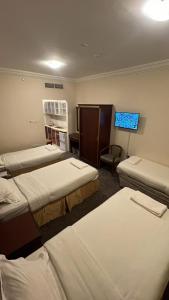 a hotel room with three beds and a tv at فندق رشيد الفضي in Az Zahrāʼ