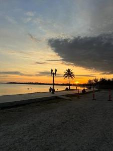 a sunset on a beach with palm trees and the water at Casa da Vovó Irene in Araruama +18 photos