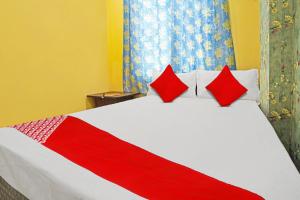 uma cama vermelha e branca com duas almofadas vermelhas em OYO Flagship Hotel Sigdi & Restaurant em Jaipur