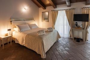 - une chambre avec un grand lit et une télévision dans l'établissement Relais Bella Rosina Pool & Spa, à Fiano