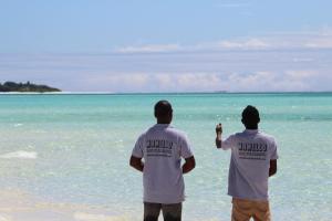 two men standing on the beach looking at the ocean at MAMELLO Beach Club Maldives in Feridhoo
