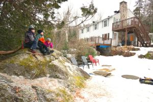 Un groupe de personnes assises sur un rocher dans la neige dans l'établissement Le Partage Lodge: Destination plein air et sociale, à Val-Morin