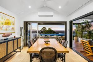 Un comedor con mesa y sillas de madera. en Sunset Lagoon ~ Noosa Luxury with Stunning Views, en Noosa Heads