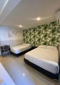Un dormitorio con 2 camas y una pared con plantas. en Apartahotel Marbella, en San Andrés