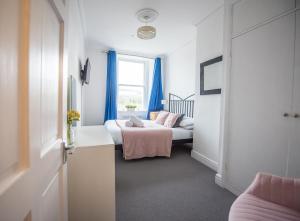 - une chambre avec 2 lits et une fenêtre avec des rideaux bleus dans l'établissement Grosvenor Pad - Lovely 2-bed Flat - FREE ON STREET PARKING, à Bath