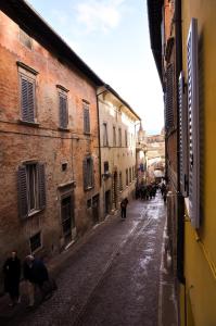 Bramante Suites Urbino في أوربينو: مجموعة من الناس يمشون في شارع في زقاق