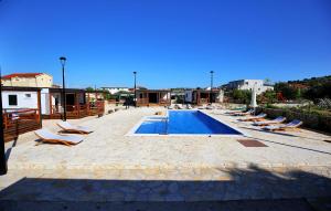 a swimming pool with lounge chairs next to a building at Beautiful Home In Murter in Murter +10 photos
