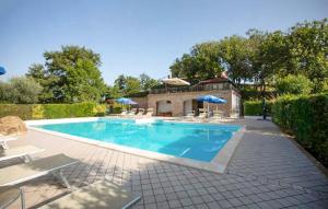 a swimming pool with chairs and umbrellas in a yard at Stunning Apartment In Gubbio With Wifi in Gubbio