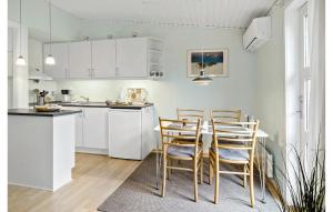 eine Küche mit weißen Schränken und einem Tisch und Stühlen in der Unterkunft Lovely Apartment In Nexø With Sauna in Neksø