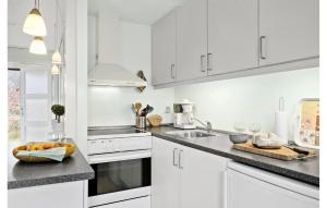 eine weiße Küche mit weißen Schränken und einer Spüle in der Unterkunft Lovely Apartment In Nexø With Sauna in Neksø + 13 Fotos