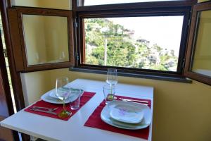 a table with two plates and glasses and a window at Casa San Pietro in Amalfi