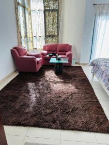a living room with a red couch and a brown rug at Tranquil Haven:King Bed, Ensuite, Master Bedroom in Ajman 