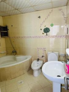 a bathroom with a tub and a toilet and a sink at Tranquil Haven:King Bed, Ensuite, Master Bedroom in Ajman 