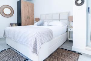 een witte slaapkamer met een groot wit bed met een houten hoofdeinde bij Holiday house with a parking space Split - 22855 in Split