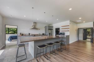 una cucina con un grande bancone e sgabelli di Tepuia Daze - Havelock Holiday Home a Picton