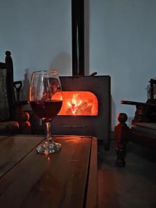 a glass of wine sitting on a table in front of a fireplace at Ruedas Negras Casa de Campo in Los Árboles