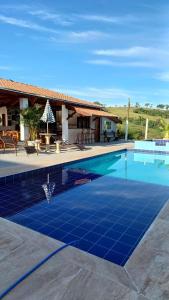 basen z niebieską podłogą wyłożoną kafelkami przed domem w obiekcie Pousada irmãos Oliveira w mieście Lindóia